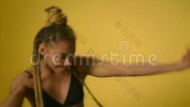 非洲女人，有非洲发型，在黄墙上跳嘻哈舞